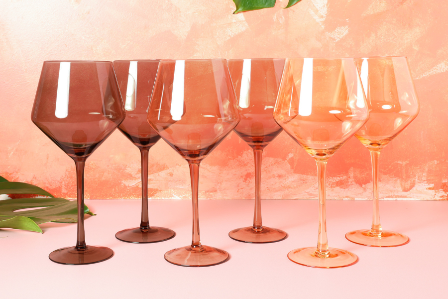 Set of nude-toned wine glasses on a peach background representing melanin skin tones