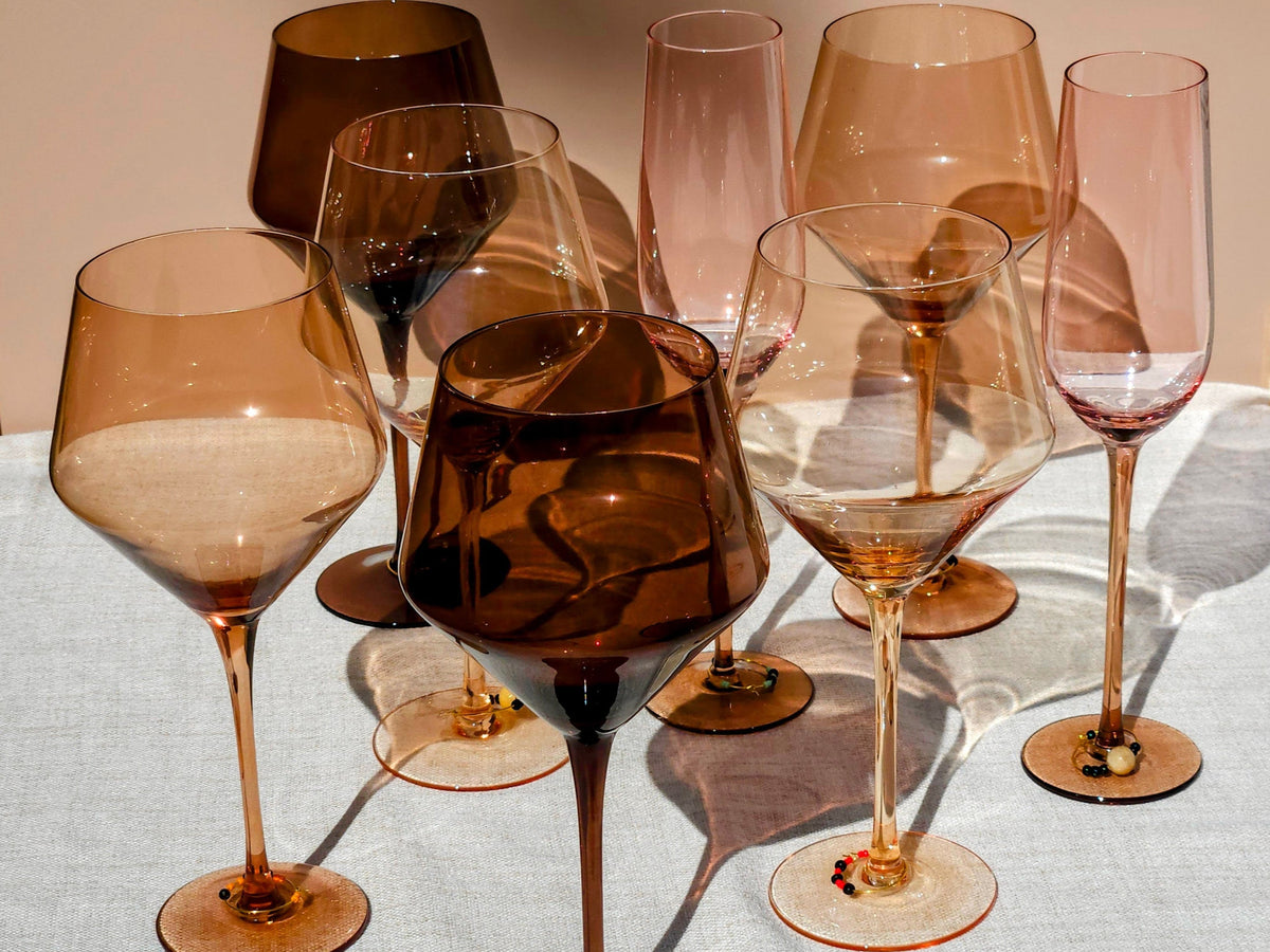 A collection of Spectrum wine glasses and champagne flutes arranged together in warm sunlight